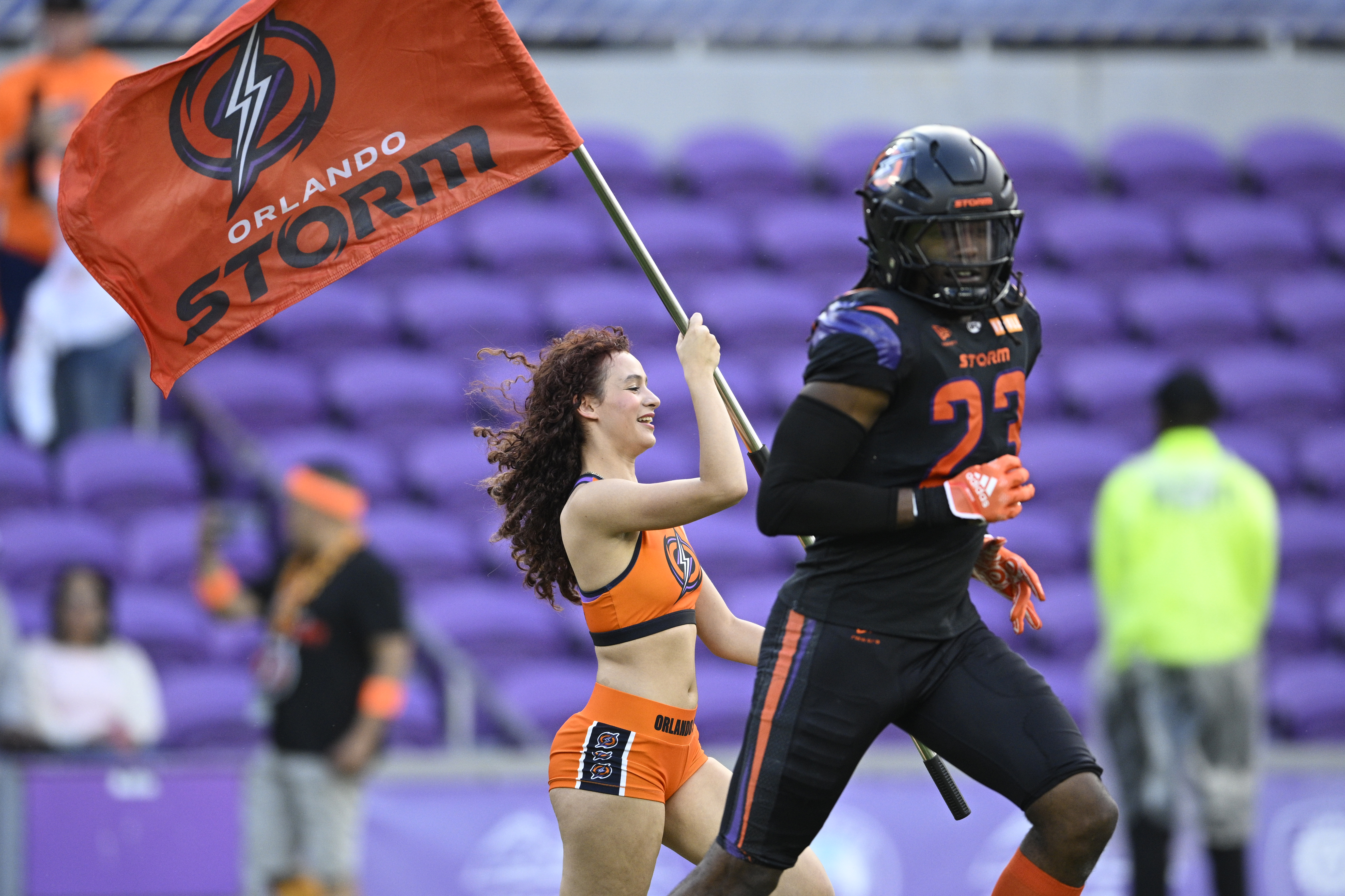 An Orlando Storm cheerleader carries a team flag onto the...