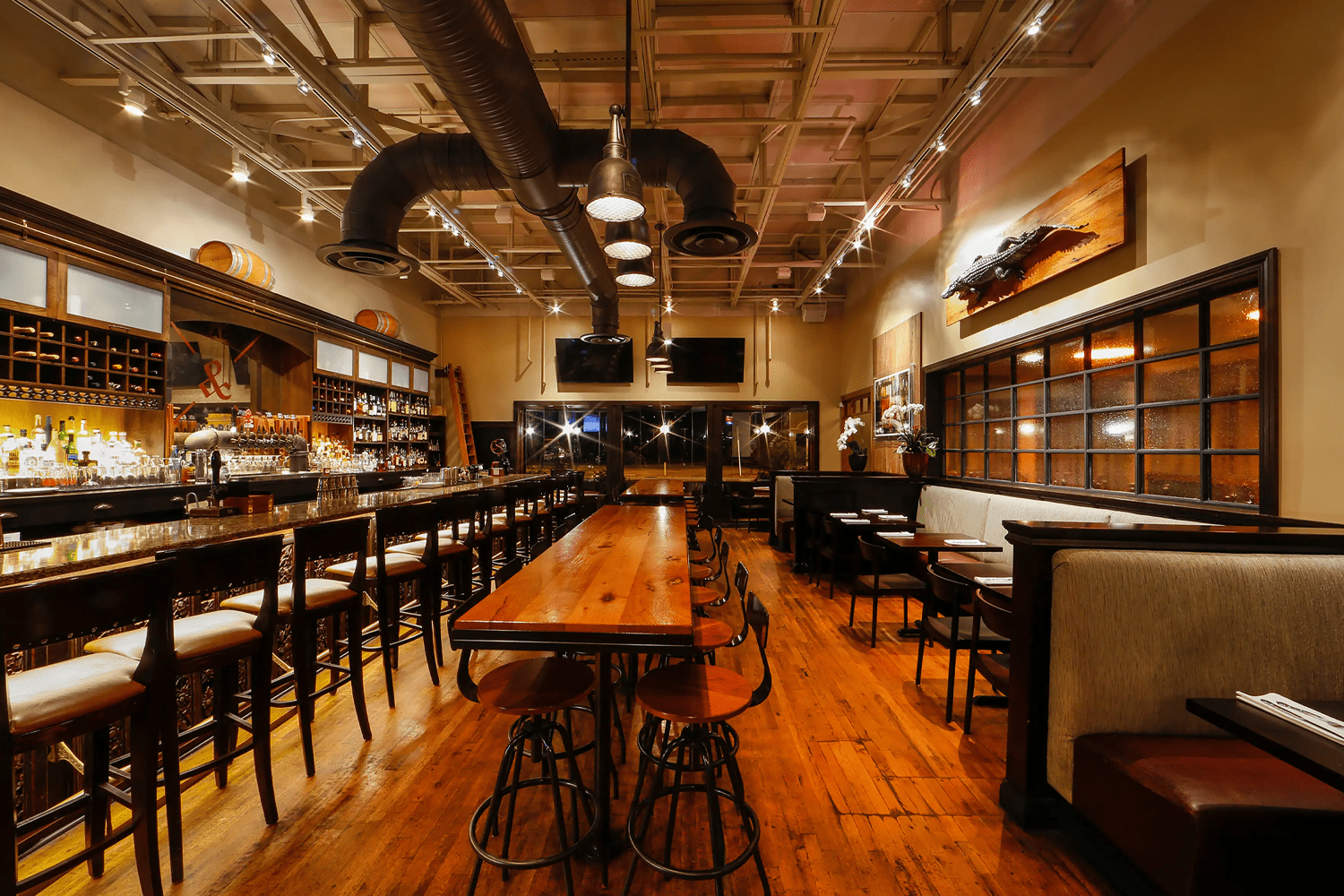Restaurant interior at The Ravenous Pig featuring a contemporary gastropub dining room with warm lighting, wood accents, a bar area and tables set for guests.