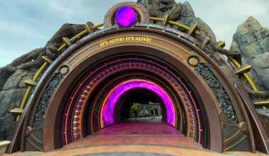 A large, decorative tunnel entrance with glowing purple lights welcomes guests into Epic Universe