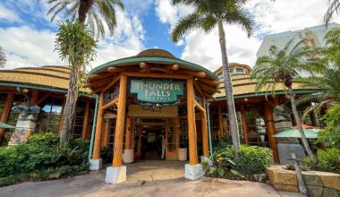 Entrance of Thunder Falls Terrace at Islands of Adventure, with palm trees and tropical-themed architecture under a blue sky.