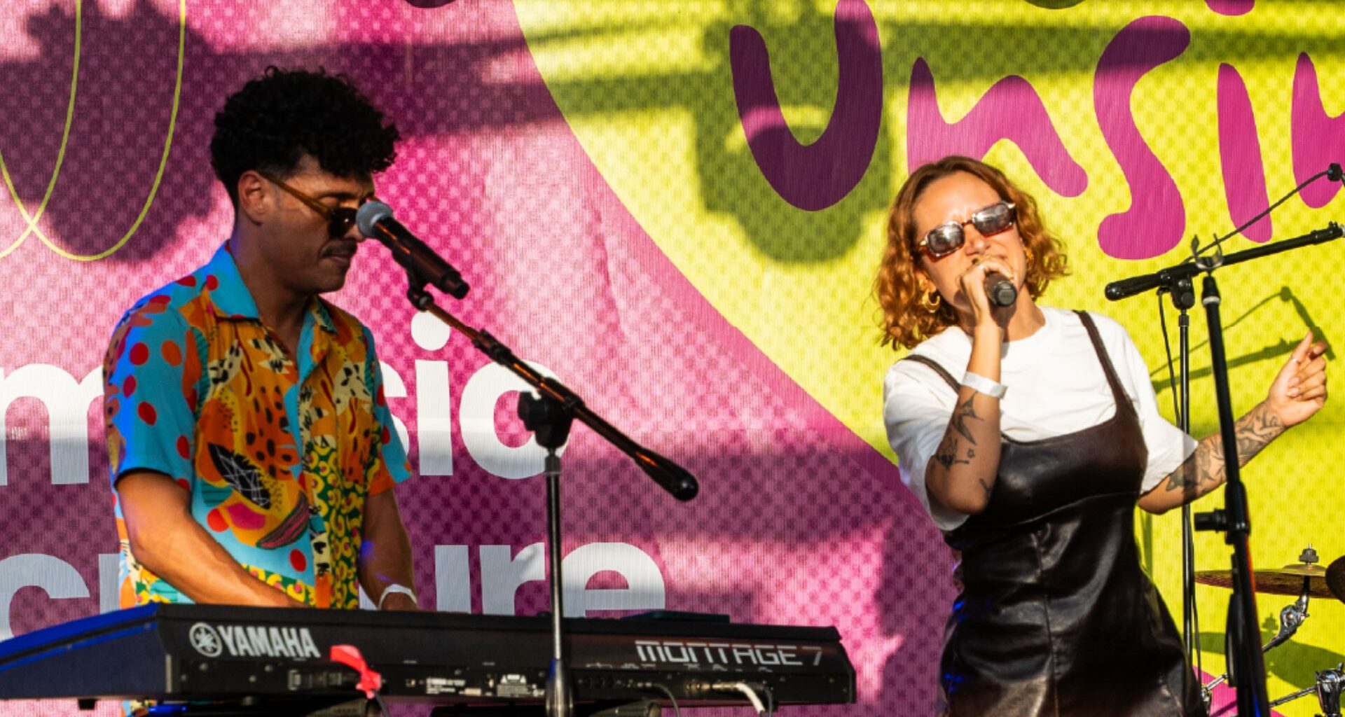 Photo of two musicians performing on stage in front of a sign that says Unsin.