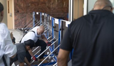 Workers install AquaFence flood barrier system at Naples hospital campus entrance
