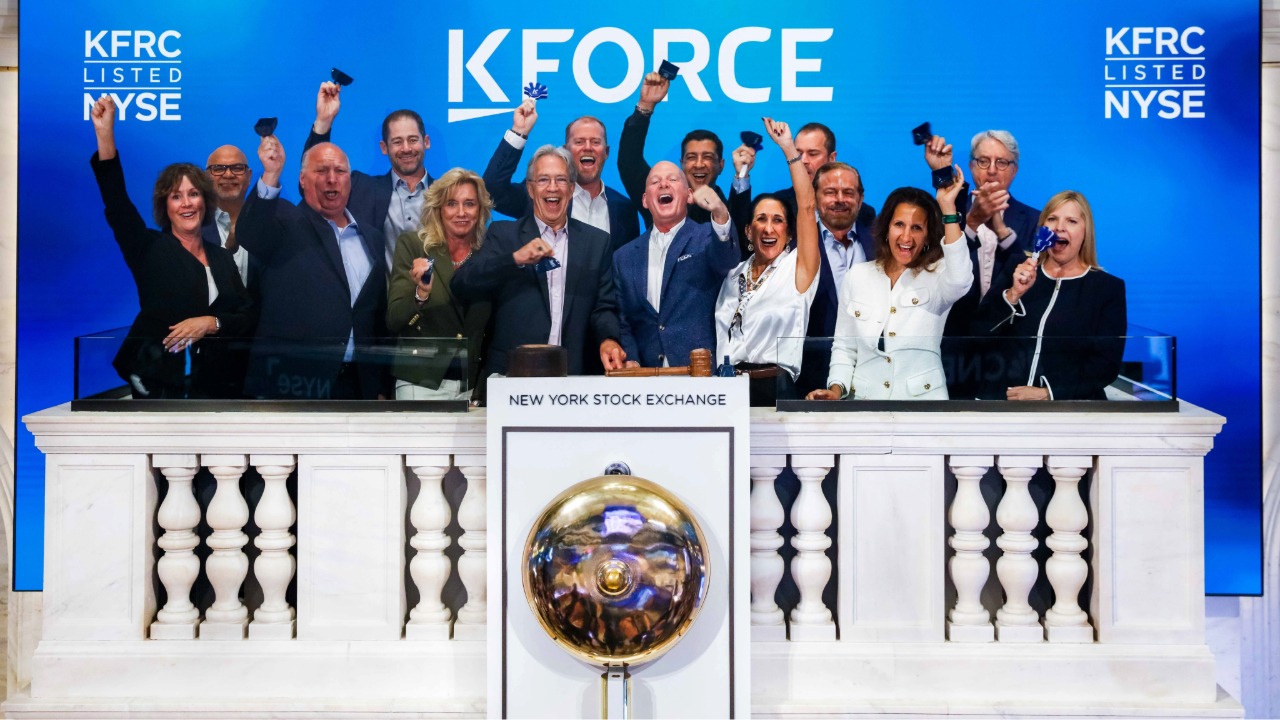 Kforce executives and team members ring the opening bell at the New York Stock Exchange in front of a Kforce-branded display.
