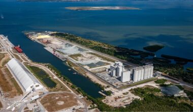 Aerial view of Port Redwing bulk terminal in Tampa Bay with storage piles, silos and docked cargo vessel
