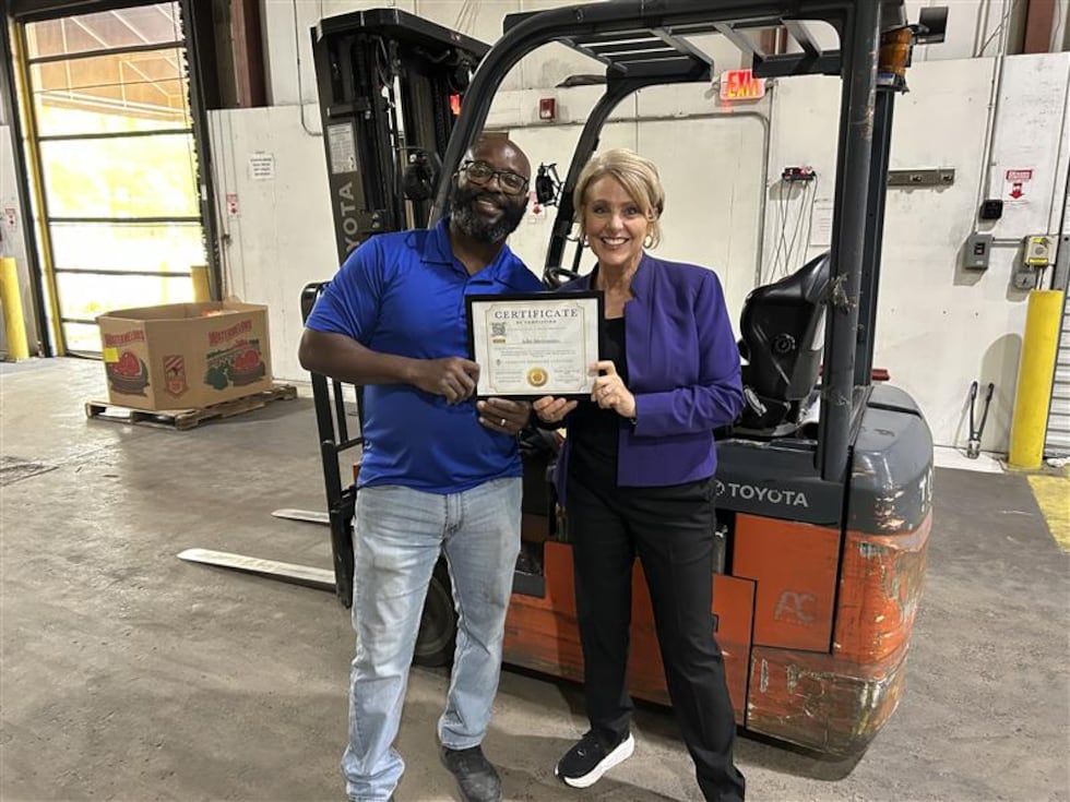 Julie proudly holds her forklift certification with Kenny Sharpe at the Second Harvest...