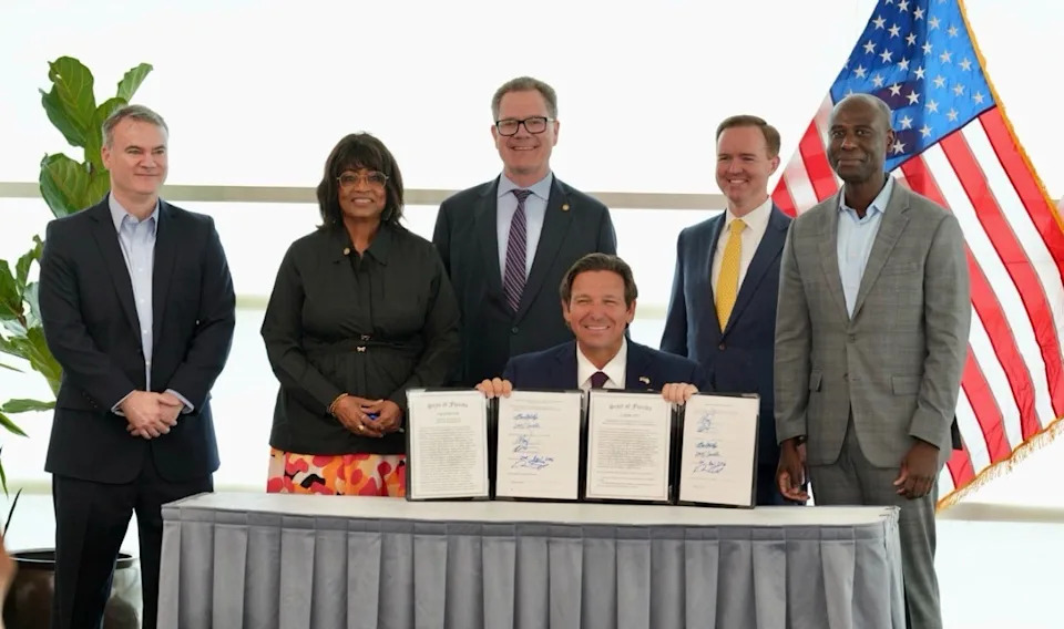 Florida state Reps. Wyman Duggan, Kiyan Michael and Dean Black, state Sen. Clay Yarborough and state Rep. Berny Jacques stand behind Gov. Ron DeSantis at a bill-signing ceremony on April 22, 2026 in Jacksonville. DeSantis signed bills barring local governments from spending taxpayer dollars on diversity, equity and inclusion programs. Black and Yarborough sponsored the legislation in the House and Senate.