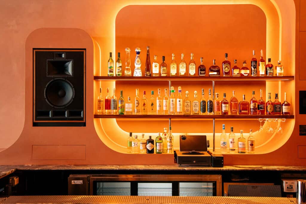 An orange bar set up of liquor and speakers