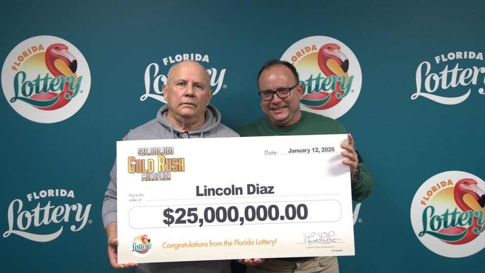 Lincoln Diaz and guest pose with an oversized check after claiming a $25 million top prize from the $25,000,000 GOLD RUSH MULTIPLIER Scratch-Off game at Florida Lottery Headquarters in Tallahassee. (Florida Lottery){ }