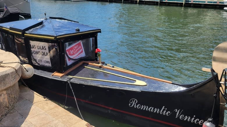 A gondola that says "Romantic Venice" on the side docked in the water