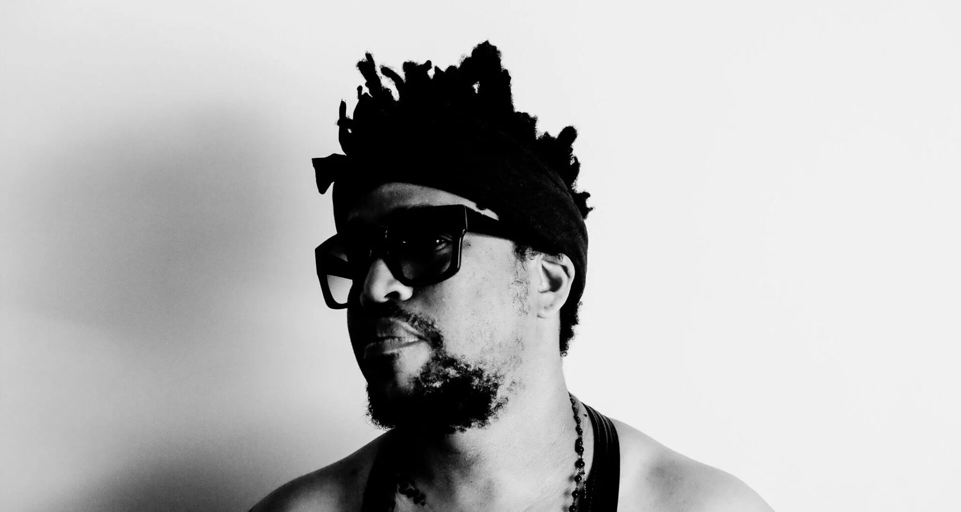 Black and white photo of a man wearing a black tank top and sunglasses.