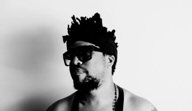 Black and white photo of a man wearing a black tank top and sunglasses.