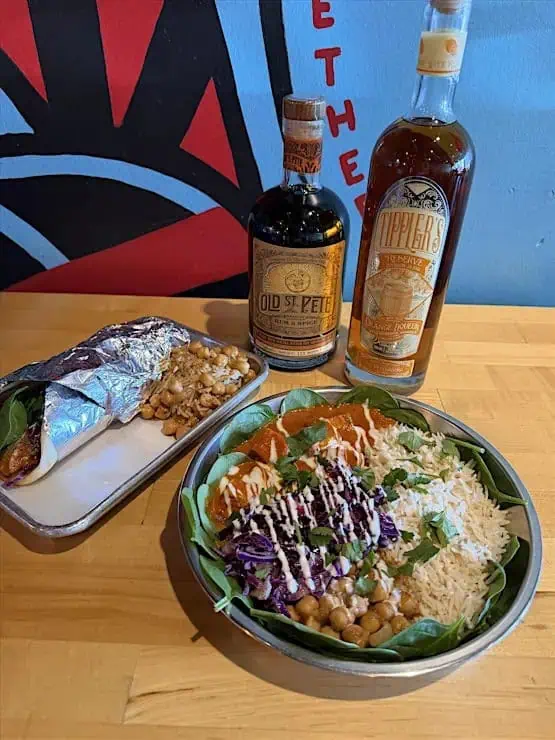 Bottles of alcohol, next to plates of Indian food