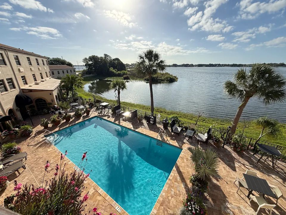 Hotel pool with lake just beyond and palm trees.