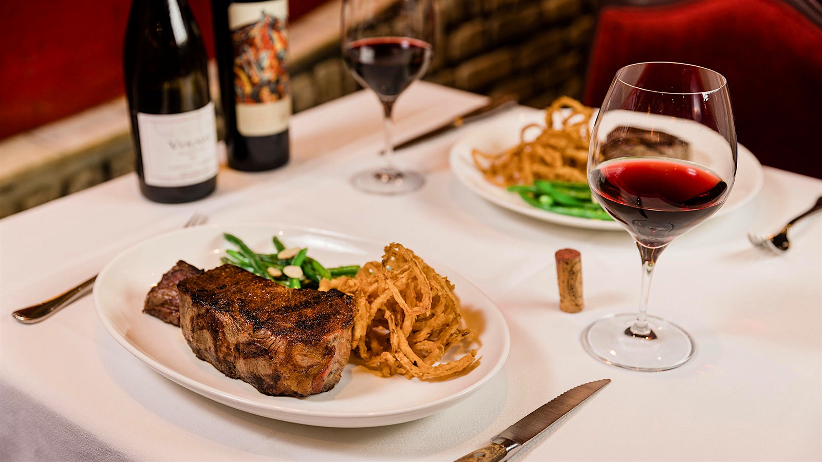  A table at Bern’s Steak House with wines and plates of steaks.