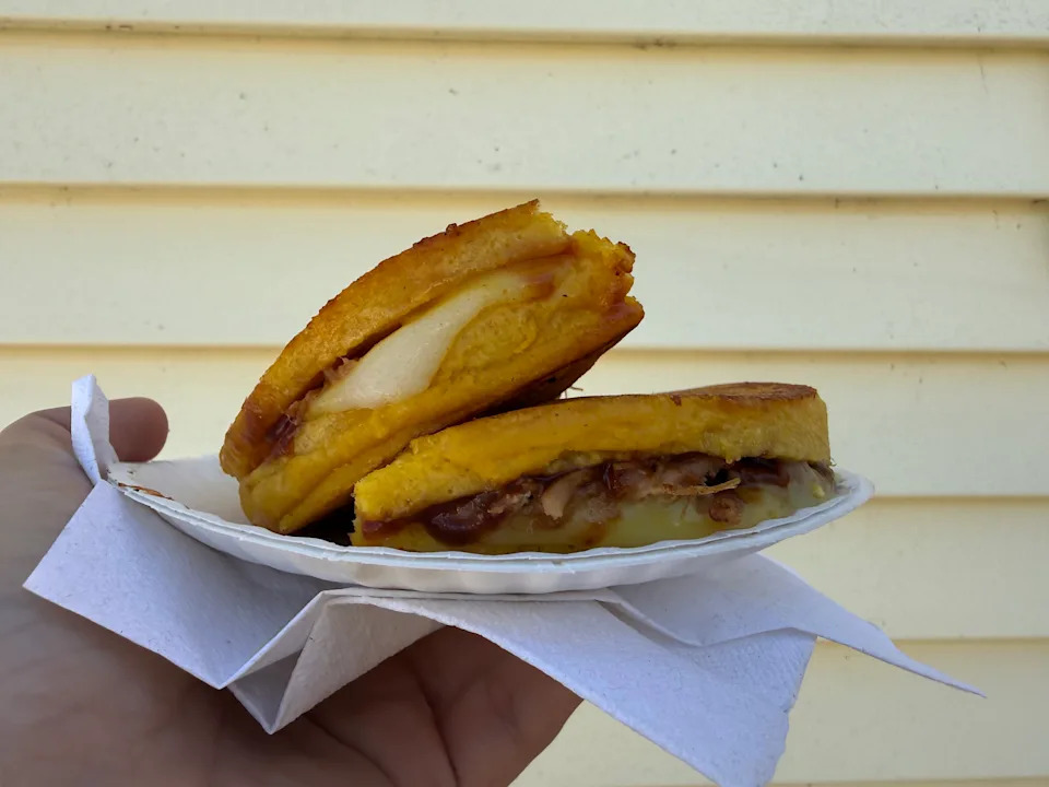 Arepa cut in half and posed in front of a yellow wall.