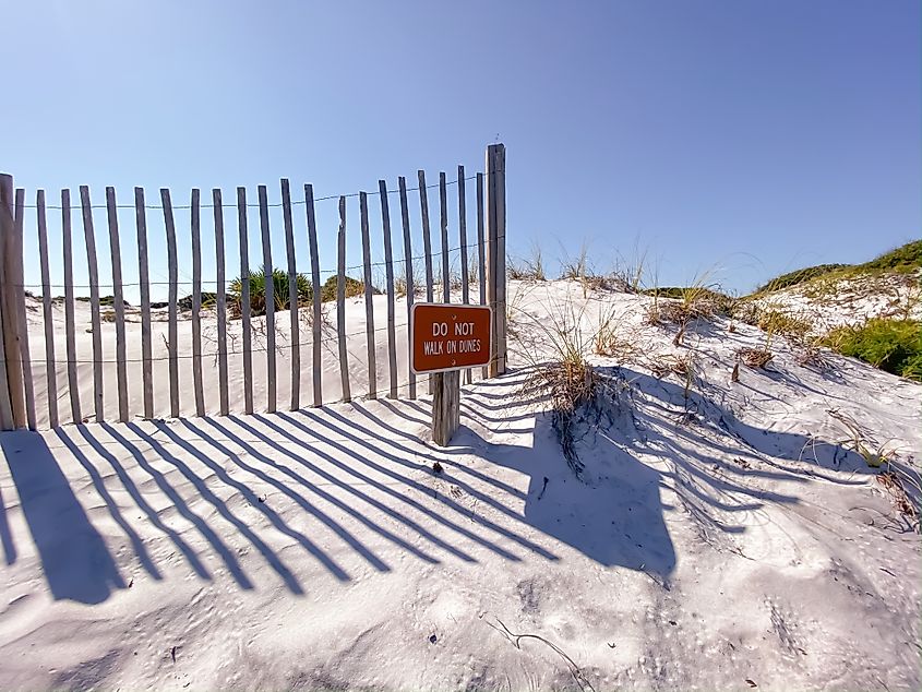 White sand dunes with sign to sat off dunes at Grayton Beach State Park in Florida