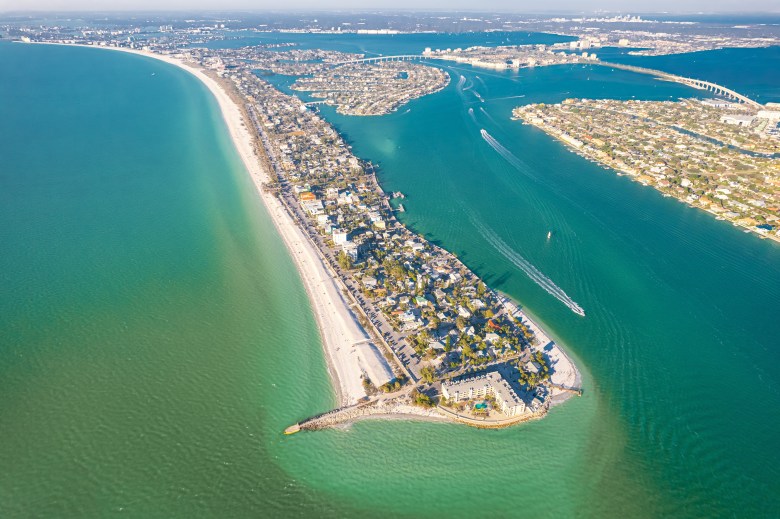erial drone view of St. Pete Beach and Pass-a-Grille Beach in Florida, showing white sand coastlines, turquoise Gulf of Mexico waters, and coastal resorts.