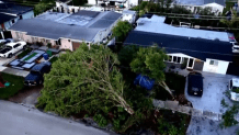 An aerial image shows a front yard at Northwest 78th Avenue and Northwest 181st Street on April 8, 2026. Two trees and a fence are knocked down.