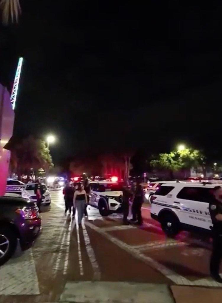 Police officers and vehicles with flashing lights at Icon Park during a takeover event.