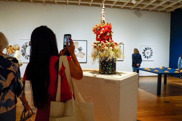 A museum guest admires the arrangement by Rebecca Valente, inspired by Dennis Scholl's A Day of Four Sunsets, part of the artist's showing of works on space exploration at the Orlando Museum of Art during Art in Bloom on Friday, April 10, 2026, the annual Council of 101 event and fundraiser. (Rich Pope/Orlando Sentinel)