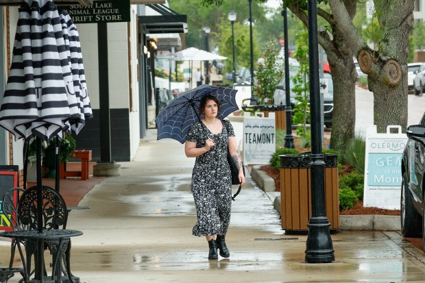 Micaela Jones keeps dry under an umbrella during a rainy walk in downtown Clermont on Tuesday, April 7, 2026. (Rich Pope/Orlando Sentinel)