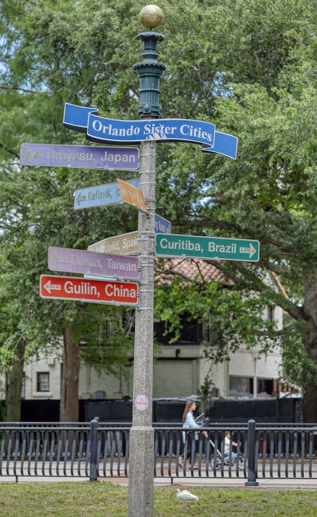 Orlando sister cities sing at Lake Eola Park, on Thursday, April 23, 2026. On the sign are Orlando's sister cities listed as: Urayasu, Japan; Keflavik, Iceland; Monterrey, Mexico; Orenburg, Russia; Valladolid, Spain; Curitiba, Brazil; Tainan, Taiwan; Guilin, China; and Seine-et-Marne, France. (Ricardo Ramirez Buxeda/ Orlando Sentinel)