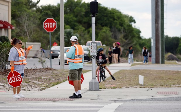 Crossing Guards wait for pedestrians cross the street at Dean Road and Flowers Avenue during dismissal at Union Park Elementary School, on Thursday, April 23, 2026. (Ricardo Ramirez Buxeda/ Orlando Sentinel)