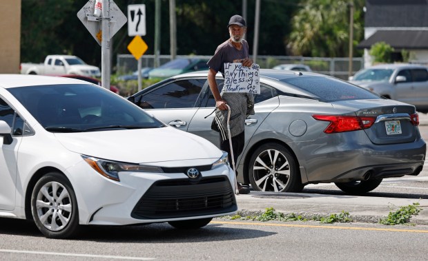 A panhandler at the intersection of East Colonial Drive and Dean Road near Union Park Elementary School, on Thursday, April 23, 2026. (Ricardo Ramirez Buxeda/ Orlando Sentinel)
