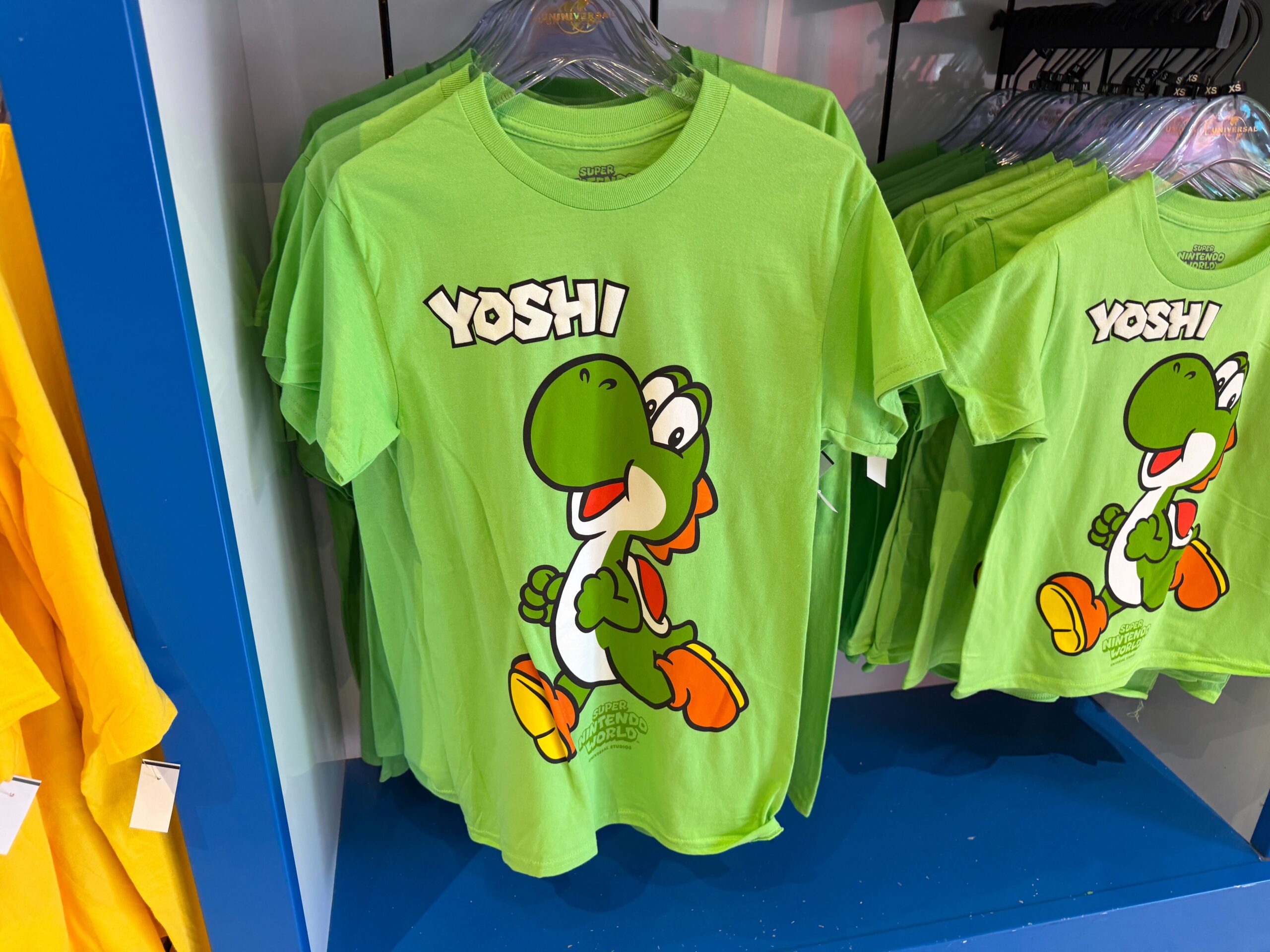 This lime green top features a dark green Yoshi with orange shoes and a red shell.