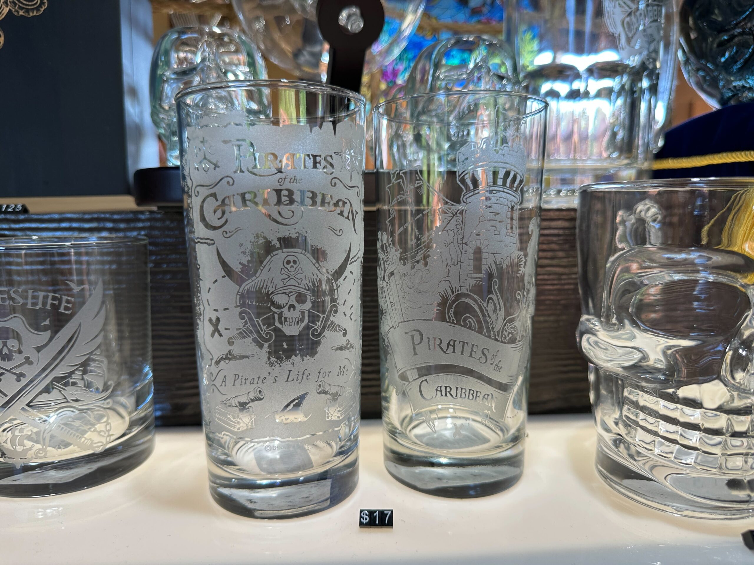 This first tall glass features a pirate skull and crossed swords against a frosted map design. The "A Pirate's Life for Me" is above a pair of cannons and a shark fin.
