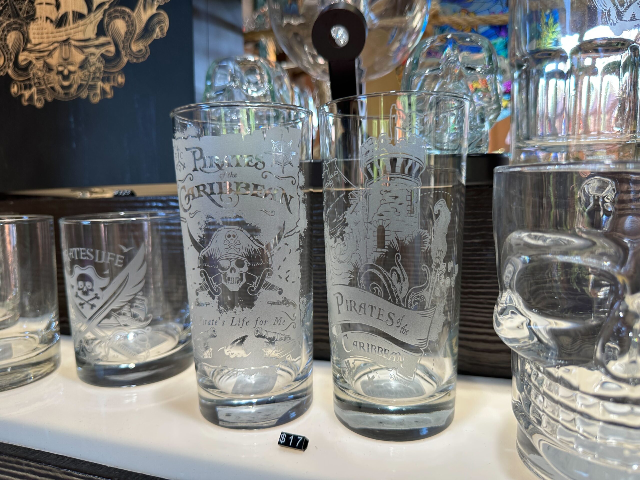 A similarly-shaped glass features a crumbling fort tower, a pirate ship, and sea creature tentacles.