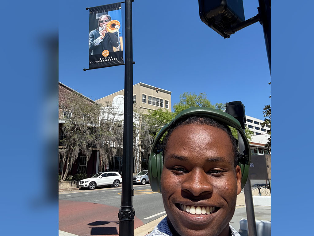 Florida A&M University alumnus Gamaliel Harris poses beneath a City of Tallahassee banner featuring his image from a past performance. Harris, a 2025 graduate, will begin Juilliard’s graduate jazz studies program this fall. (Photo courtesy: Gamaliel Harris)