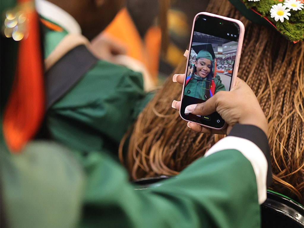 Spring class of 2026 Graduate takes a selfie in the audience.