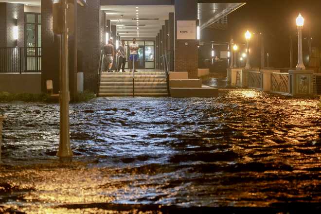 Florida Residents Prepare For Hurricane Milton FORT MYERS BEACH, FLORIDA - OCTOBER 09: People look out at surge waters flooding the street from their building after Hurricane Milton came ashore in the Sarasota area on October 09, 2024, in Fort Myers, Florida. People are waiting to assess the damage after the Cat 3 hurricane came ashore. (Photo by Joe Raedle/Getty Images)
