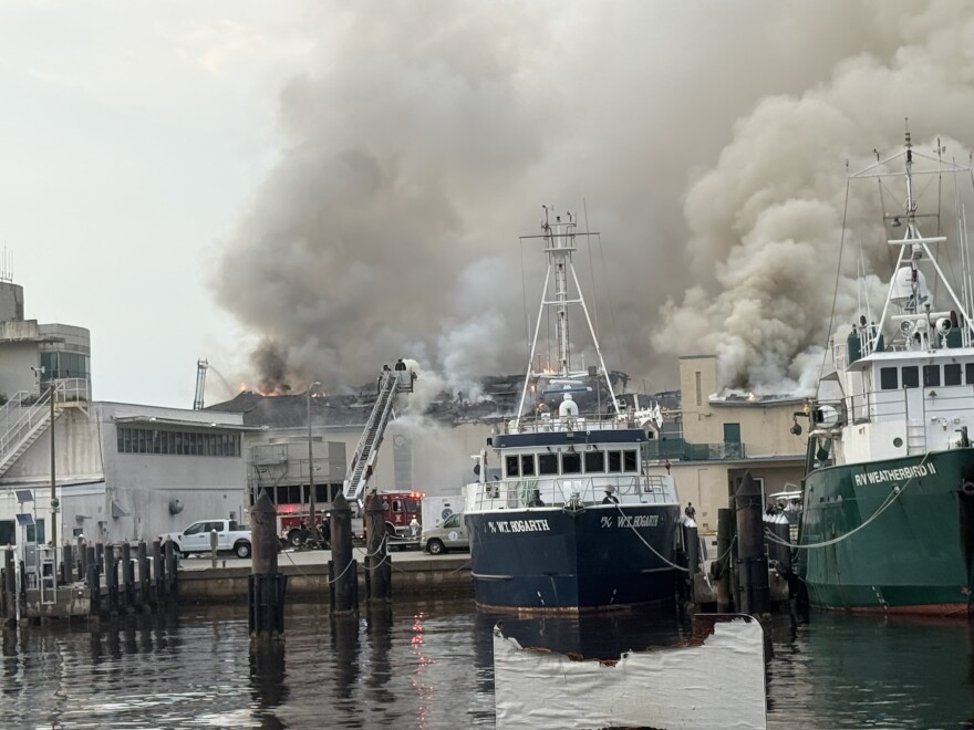 multiple buildings with flames and large plume of gray smoke coming from one of the buildings