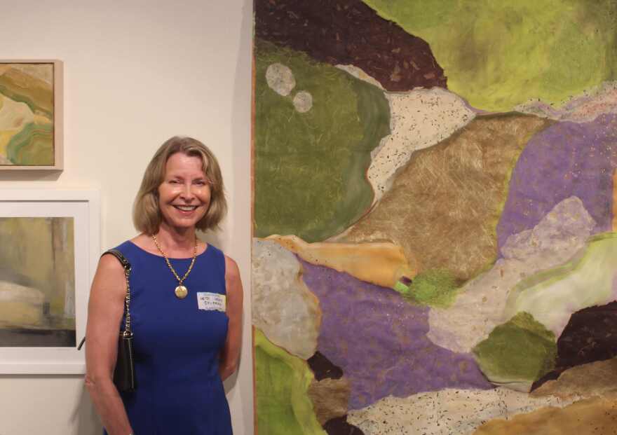 Abstract artist Heidi Lewis Coleman poses next to painting from her 'Dreamscape' series at opening of solo show in the Foulds Theatre Lobby at Alliance for the Arts.