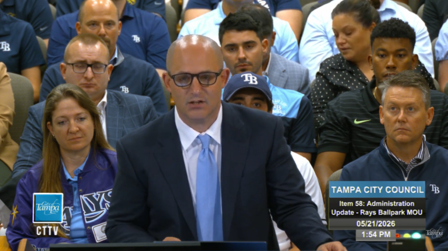 Man with glasses speaking at a podium