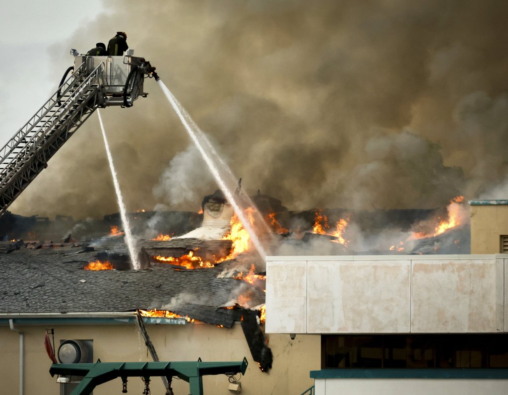 Firefighters on a ladder truck douse a fire engulfing the roof of a building at the University of South Florida campus.