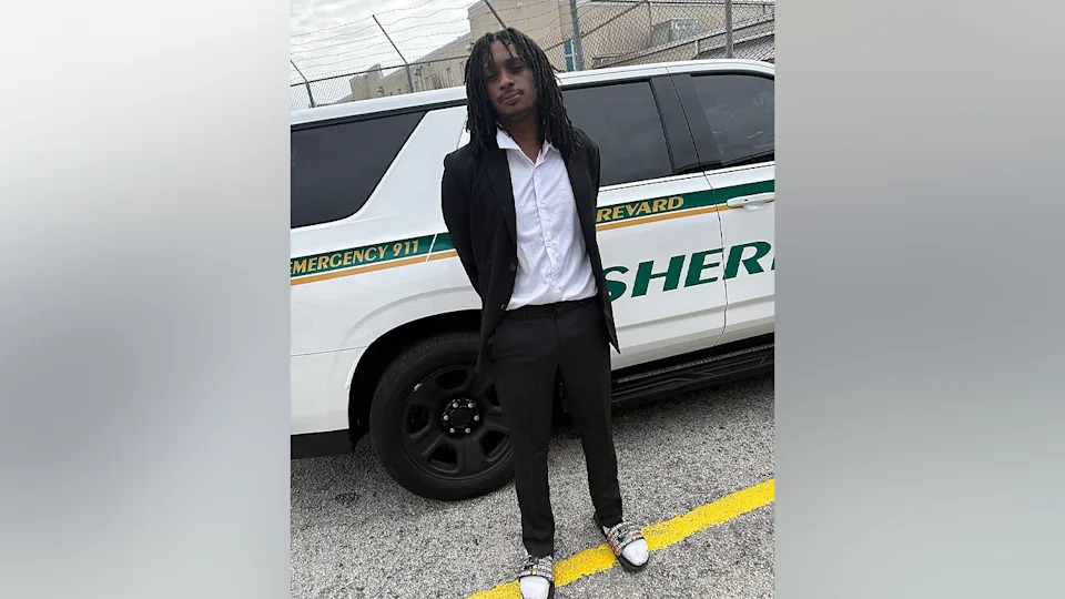 Christopher Jones stands in a suit and slide sandals after being arrested for allegedly driving over 100 mph in Brevard County, Florida
