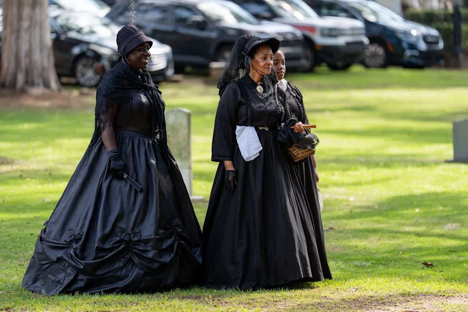 Women dressed in mourning dresses stand in the Old City Cemetery during the grave decorating ceremony on Emancipation Day.