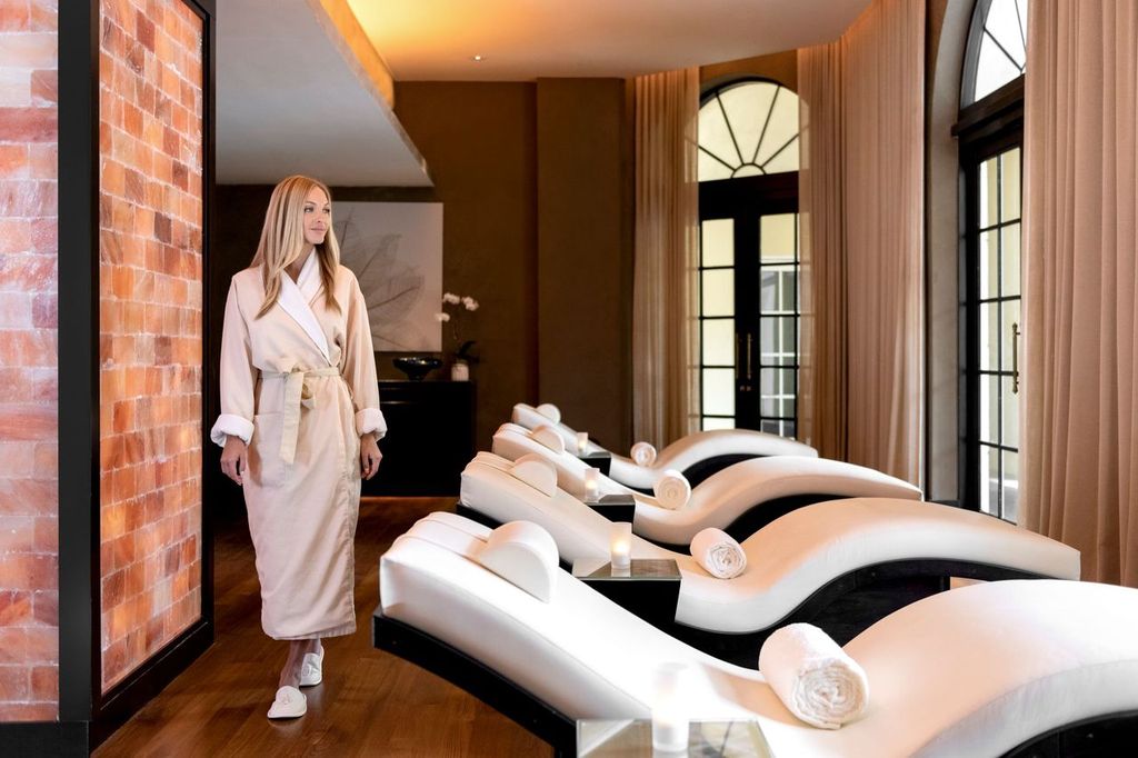 photo of a woman in a robe walking past treatment beds in a spa