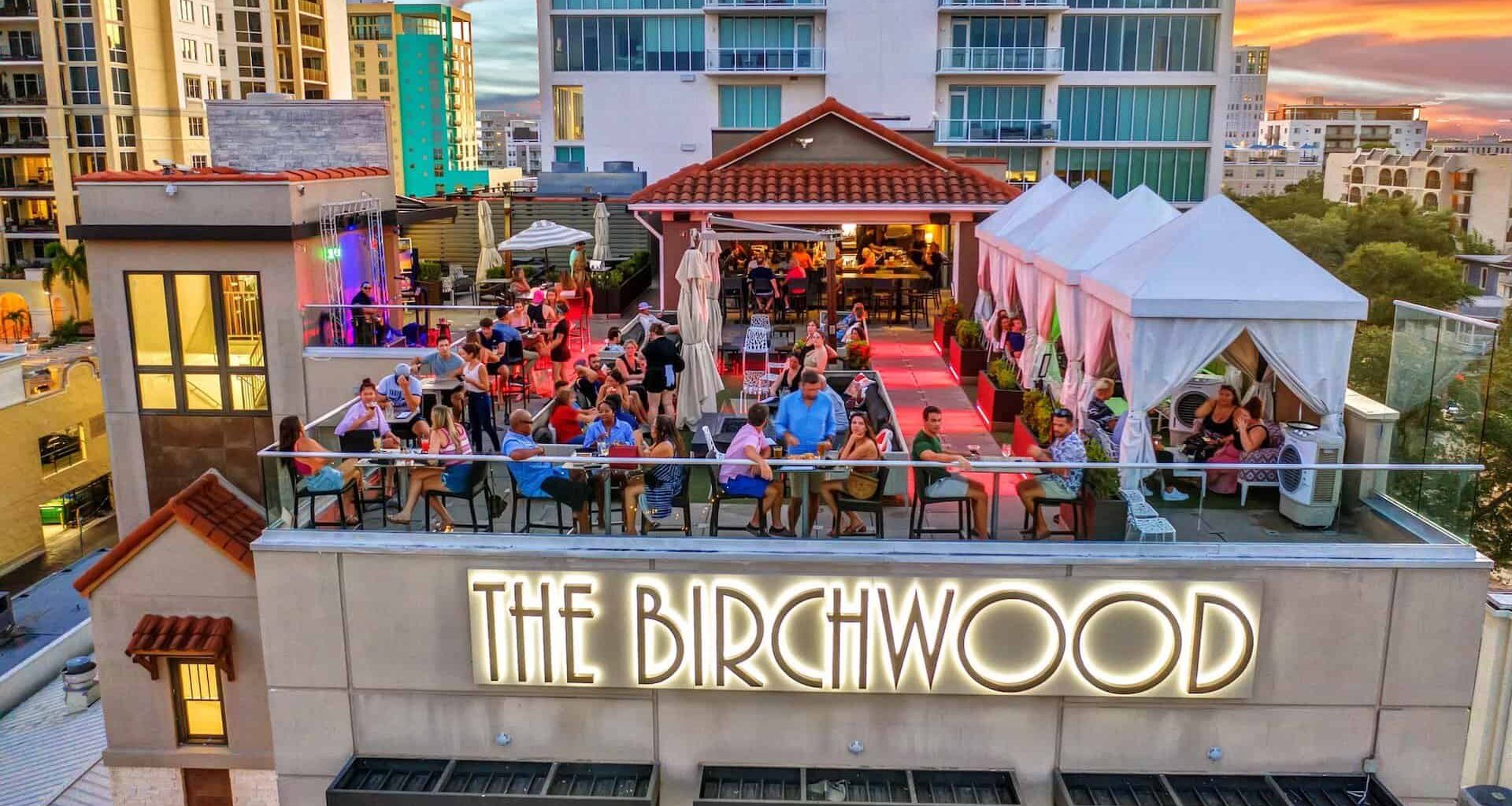 a rooftop bar with multiple people standing on the top