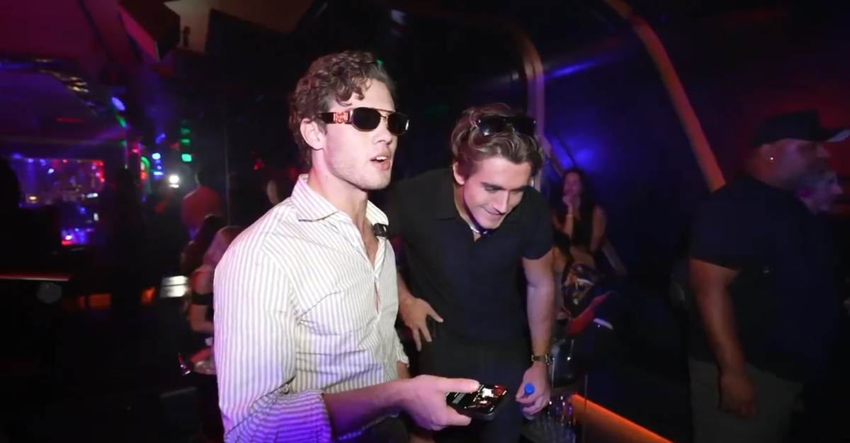 A photo of a man wearing sunglasses inside a club.