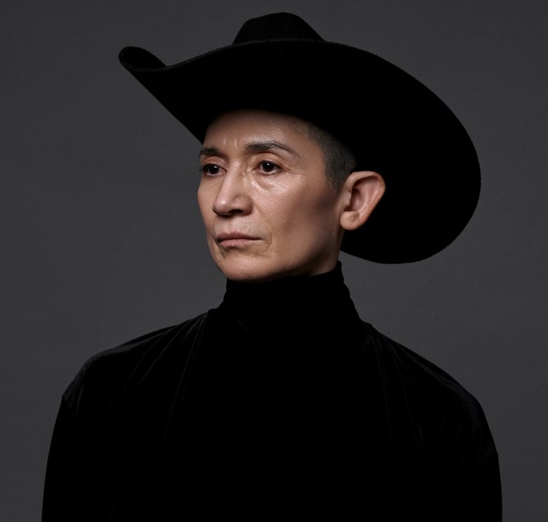Dora Arreola poses in a black turtleneck and cowboy hat against a dark background