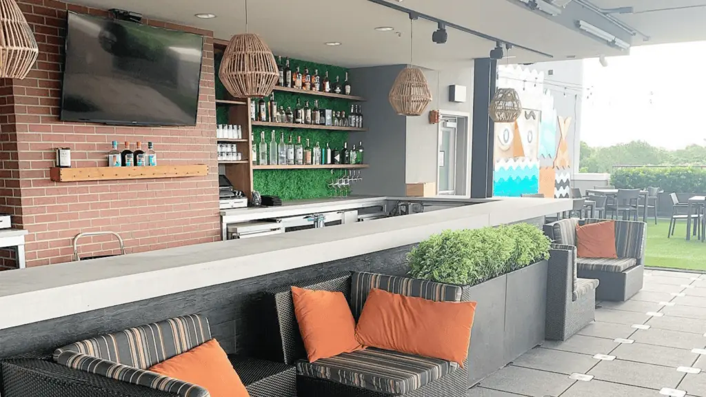 Rooftop bar with orange sofa cushions and green turf
