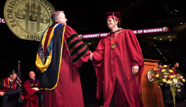 Graduates walk across the stage in garnet and black regalia during the Herbert Wertheim College of Business commencement ceremony at Florida State University.