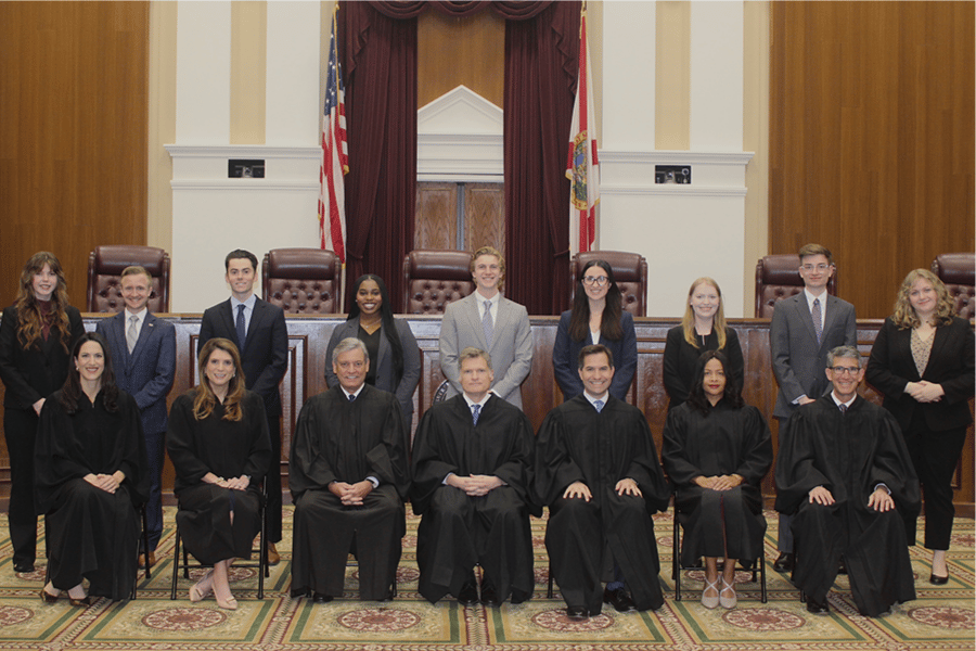 Standing: Supreme Court Fellows Seated (L-R): Justice Meredith L. Sasso, Justice Jamie R. Grosshans, Justice Jorge Labarga, Chief Justice Carlos G. Muñiz, Justice John D. Couriel, Justice Renatha Francis, and Justice Adam S. Tanenbaum