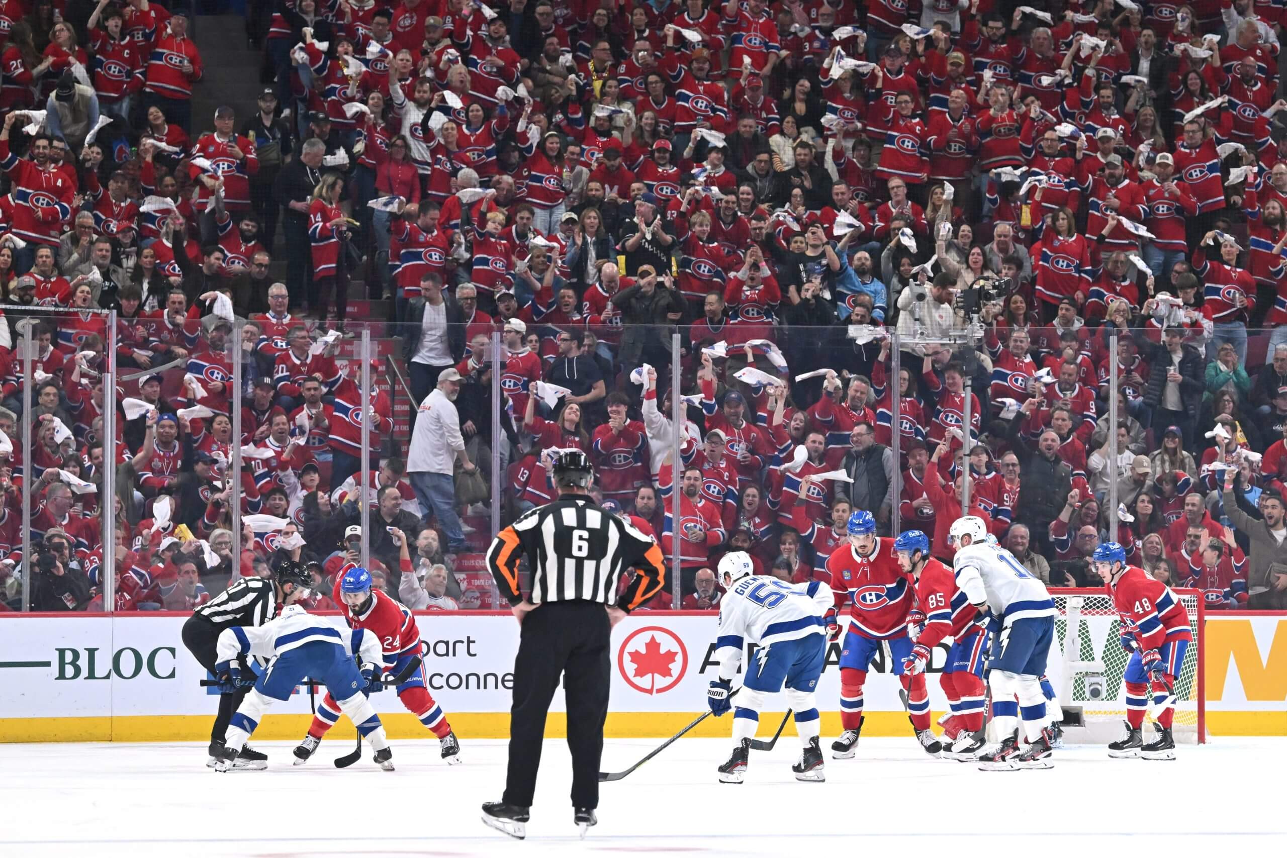 Fans wave towels as a referee is about to drop the puck for a faceoff in a Canadiens-Lightning game.