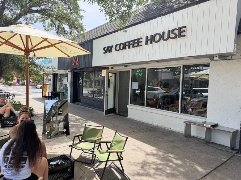 Exterior of Say Coffee House with people sitting under umbrellas outside.