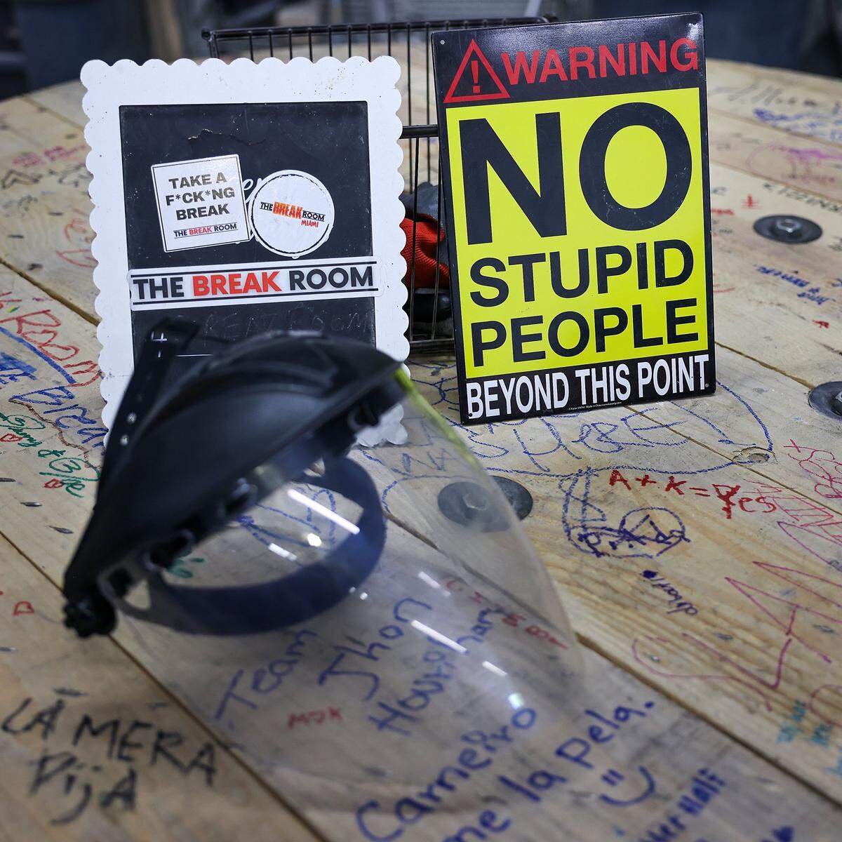 A sign reading "No stupid people beyond this point" is displayed next to a protective helmet with a face shield at The Break Room Miami, reminding guests to prioritize safety before entering the rage rooms on Thursday, May 7, 2026.